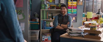 Movie still from “Middle School: The Worst Years of My Life” (2016), directed by Steve Carr – A man sitting at a desk in front of a book shelf; Medium shot, Over the shoulder angle