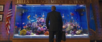 Movie still from “Middle School: The Worst Years of My Life” (2016), directed by Steve Carr – A man standing in front of a fish tank; Wide shot, Over the shoulder angle