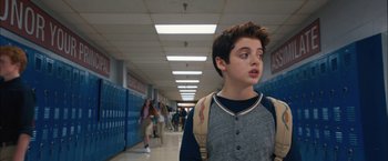 Movie still from “Middle School: The Worst Years of My Life” (2016), directed by Steve Carr – A boy with a backpack walking down a school hallway; Medium shot, Over the shoulder angle