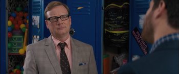 Movie still from “Middle School: The Worst Years of My Life” (2016), directed by Steve Carr – A man in a suit and tie standing in front of two lockers; Close Up shot, Over the shoulder angle