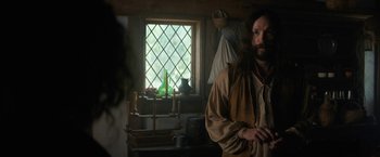 Movie still from “Fear Street: Part Three - 1666” (2021), directed by Leigh Janiak – A man standing in front of a window in a room; Medium shot, Over the shoulder angle