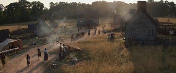 Movie still from “Fear Street: Part Three - 1666” (2021), directed by Leigh Janiak – A group of people standing in a field near a building; Extreme Wide shot, High angle