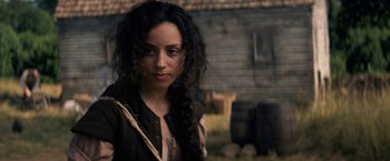 Movie still from “Fear Street: Part Three - 1666” (2021), directed by Leigh Janiak – A woman with long black hair standing in front of a building; Close Up shot, Over the shoulder angle