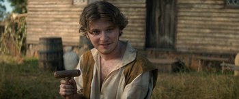 Movie still from “Fear Street: Part Three - 1666” (2021), directed by Leigh Janiak – A young man holding a hammer while standing in front of a house; Close Up shot, High angle