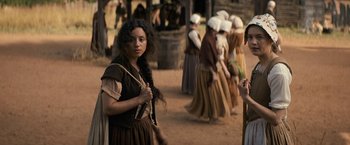 Movie still from “Fear Street: Part Three - 1666” (2021), directed by Leigh Janiak – A woman in a brown dress holding a rope; Medium shot, Over the shoulder angle