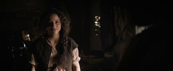 Movie still from “Fear Street: Part Three - 1666” (2021), directed by Leigh Janiak – A woman with long curly hair standing in a dark room; Close Up shot, Over the shoulder angle