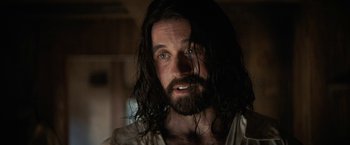 Movie still from “Fear Street: Part Three - 1666” (2021), directed by Leigh Janiak – A person with long hair and a beard; Close Up shot, Over the shoulder angle
