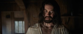 Movie still from “Fear Street: Part Three - 1666” (2021), directed by Leigh Janiak – A man with long hair and a beard stares at the camera; Close Up shot, Over the shoulder angle