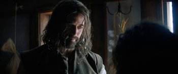 Movie still from “Fear Street: Part Three - 1666” (2021), directed by Leigh Janiak – A man with long hair and a goatee; Close Up shot, Over the shoulder angle