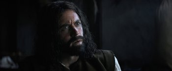Movie still from “Fear Street: Part Three - 1666” (2021), directed by Leigh Janiak – A man with long black hair and a beard; Close Up shot, Over the shoulder angle