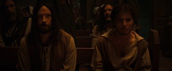 Movie still from “Fear Street: Part Three - 1666” (2021), directed by Leigh Janiak – A group of people sitting in a room; Medium shot, High angle