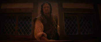 Movie still from “Fear Street: Part Three - 1666” (2021), directed by Leigh Janiak – A man with a beard and a mustache in a room; Medium shot, Low angle