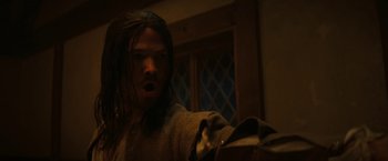 Movie still from “Fear Street: Part Three - 1666” (2021), directed by Leigh Janiak – A man with long black hair is holding a bag; Close Up shot, Low angle