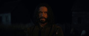 Movie still from “Fear Street: Part Three - 1666” (2021), directed by Leigh Janiak – A man with long black hair and a beard; Close Up shot, Over the shoulder angle