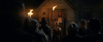 Movie still from “Fear Street: Part Three - 1666” (2021), directed by Leigh Janiak – A group of people standing in front of a building; Wide shot, Low angle