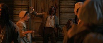 Movie still from “Fear Street: Part Three - 1666” (2021), directed by Leigh Janiak – A man holding a wooden stick in front of a woman; Medium shot, Over the shoulder angle