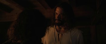 Movie still from “Fear Street: Part Three - 1666” (2021), directed by Leigh Janiak – A man with long dark hair wearing a white shirt; Close Up shot, Over the shoulder angle