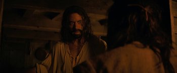 Movie still from “Fear Street: Part Three - 1666” (2021), directed by Leigh Janiak – A man with long hair and a goatee stares at the camera; Close Up shot, Over the shoulder angle