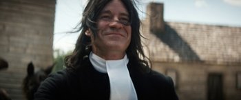 Movie still from “Fear Street: Part Three - 1666” (2021), directed by Leigh Janiak – A man with long black hair wearing a white tie; Close Up shot, Low angle