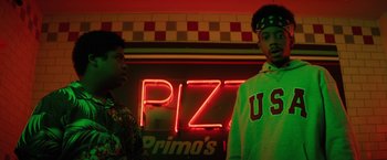 Movie still from “Fear Street: Part Three - 1666” (2021), directed by Leigh Janiak – Two young men standing in front of a neon pizza sign; Medium shot, Low angle