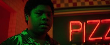 Movie still from “Fear Street: Part Three - 1666” (2021), directed by Leigh Janiak – A young man is standing in front of a neon sign; Close Up shot, Low angle