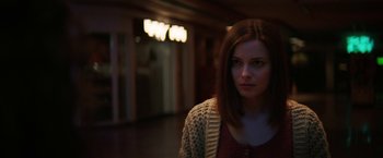 Movie still from “Fear Street: Part Three - 1666” (2021), directed by Leigh Janiak – A woman standing in a room with lights in the background; Close Up shot, Over the shoulder angle