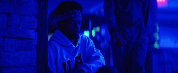 Movie still from “Fear Street: Part Three - 1666” (2021), directed by Leigh Janiak – A man in a white hoodie is sitting in a dark room; Close Up shot, Low angle