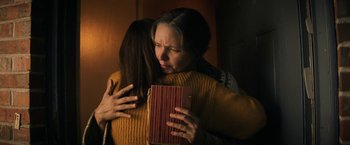 Movie still from “Fear Street: Part Three - 1666” (2021), directed by Leigh Janiak – Two women hugging and one holding a book; Close Up shot, Low angle