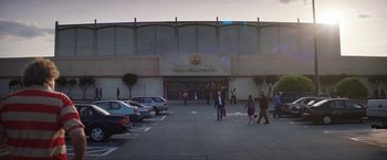 Movie still from “Fear Street: Part Three - 1666” (2021), directed by Leigh Janiak – People are walking in front of a shopping mall; Extreme Wide shot, High angle