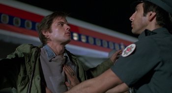 Movie still from “Midnight Express” (1978), directed by Alan Parker – A man being held down by a police officer; Medium shot, Over the shoulder angle
