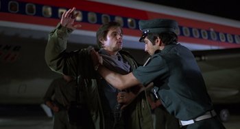 Movie still from “Midnight Express” (1978), directed by Alan Parker – A man being held down by another man in a military uniform; Medium shot, Low angle