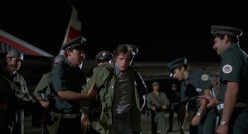 Movie still from “Midnight Express” (1978), directed by Alan Parker – A group of men standing next to each other on a field; Wide shot, Over the shoulder angle