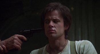 Movie still from “Midnight Express” (1978), directed by Alan Parker – A young man holding a gun up to his face; Close Up shot, Low angle