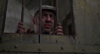 Movie still from “Midnight Express” (1978), directed by Alan Parker – A man with a hat is looking through a jail cell window; Close Up shot, Low angle
