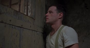 Movie still from “Midnight Express” (1978), directed by Alan Parker – A man standing in front of a wall looking to the side; Close Up shot, Low angle