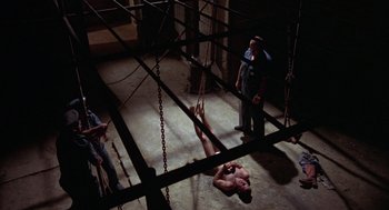 Movie still from “Midnight Express” (1978), directed by Alan Parker – A man in chains hanging from the ceiling; Wide shot, Overhead angle