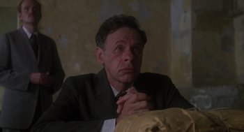 Movie still from “Midnight Express” (1978), directed by Alan Parker – A man in a suit and tie sitting in front of a wall; Close Up shot, Low angle