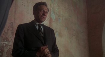 Movie still from “Midnight Express” (1978), directed by Alan Parker – A man in a suit and tie standing in front of a wall; Medium shot, Low angle