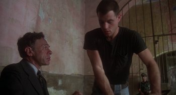 Movie still from “Midnight Express” (1978), directed by Alan Parker – Two men are talking in an old room; Medium shot, Low angle