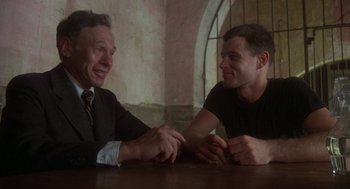 Movie still from “Midnight Express” (1978), directed by Alan Parker – Two men sitting at a table talking to each other; Medium shot, Low angle