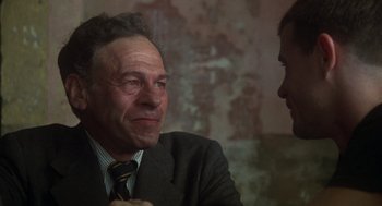 Movie still from “Midnight Express” (1978), directed by Alan Parker – An older man wearing a suit and a tie; Close Up shot, Over the shoulder angle