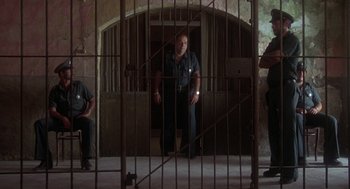 Movie still from “Midnight Express” (1978), directed by Alan Parker – A man standing behind bars in a jail cell; Wide shot, High angle