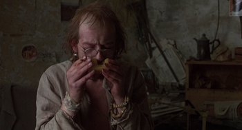 Movie still from “Midnight Express” (1978), directed by Alan Parker – A man with a beard and glasses eating a banana; Close Up shot, Over the shoulder angle