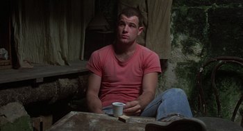 Movie still from “Midnight Express” (1978), directed by Alan Parker – A man sitting at a table with a cup of coffee; Medium shot, Low angle