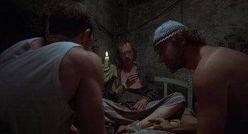 Movie still from “Midnight Express” (1978), directed by Alan Parker – A group of men sitting on top of a bed next to each other; Medium shot, High angle