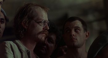 Movie still from “Midnight Express” (1978), directed by Alan Parker – A group of men standing next to each other in a room; Close Up shot, Over the shoulder angle