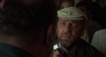 Movie still from “Midnight Express” (1978), directed by Alan Parker – An old man wearing a hat and a tie; Close Up shot, Over the shoulder angle
