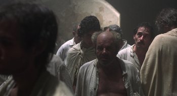 Movie still from “Midnight Express” (1978), directed by Alan Parker – A group of men standing around in a room; Medium shot, High angle