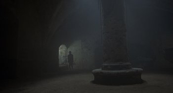 Movie still from “Midnight Express” (1978), directed by Alan Parker – A man standing in a dark room next to a pillar; Extreme Wide shot, High angle
