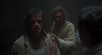 Movie still from “Midnight Express” (1978), directed by Alan Parker – Two men in a dark room one of them is holding a shirt; Medium shot, Low angle